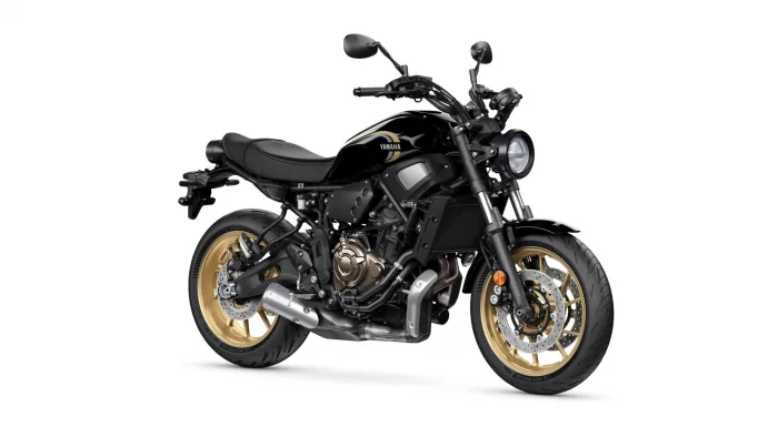 Black Yamaha sport motorcycle seen from the side with gold alloy wheels and prominent front headlight shine.