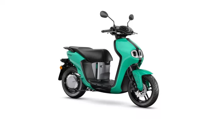 Teal scooter facing right, black seat, and front headlight visible; partial view of wheels and body.