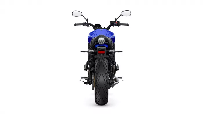 Rear view of a blue sport motorcycle, showing the wide rear tire, round taillight, and dual mirrors.