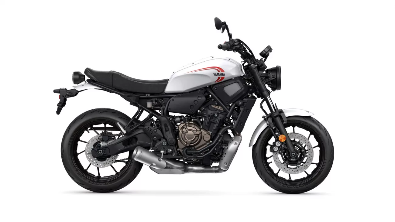 Side view of a white Yamaha motorcycle with black frame and exposed engine, showing red Yamaha logo on the fuel tank and front disc brakes