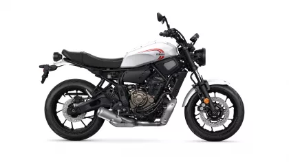Side view of a white Yamaha motorcycle with black frame and exposed engine, showing red Yamaha logo on the fuel tank and front disc brakes