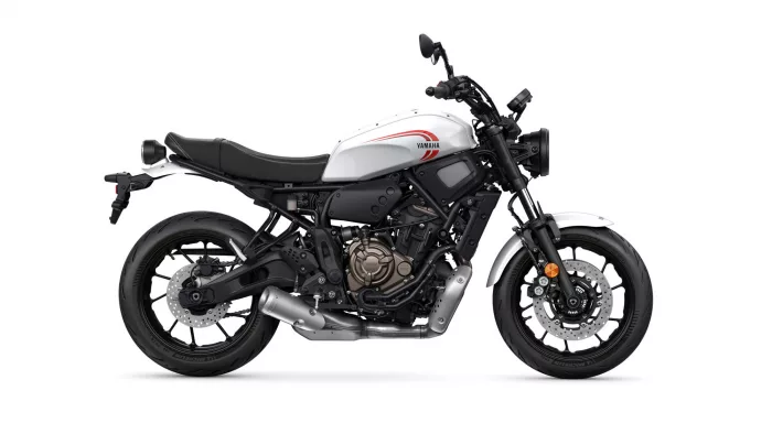 Side view of a white Yamaha motorcycle with black frame and exposed engine, showing red Yamaha logo on the fuel tank and front disc brakes