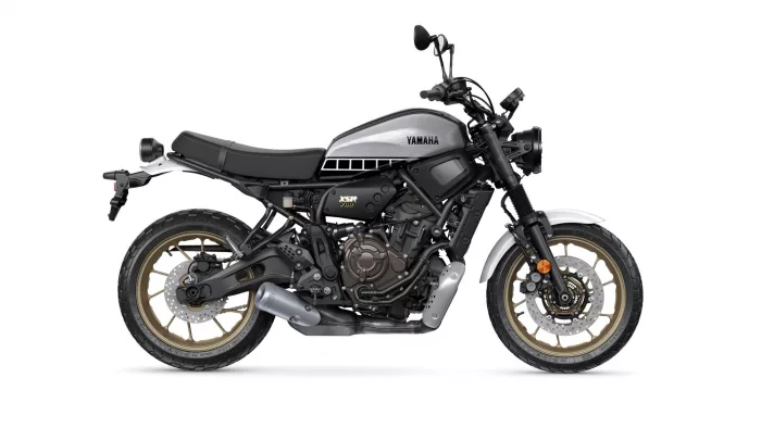 Side view of a Yamaha XSR700 motorcycle with a silver fuel tank and gold wheels, shown in profile.