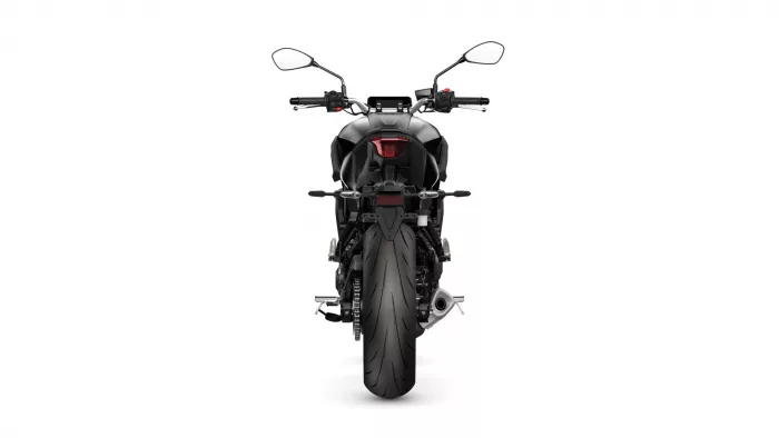 Rear view of a black sport motorcycle against a white backdrop, showing taillight, exhaust, and wide rear tire.