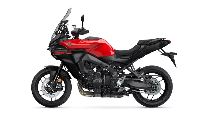 Side view of a red Yamaha Tracer adventure motorcycle with a tall windscreen and black chassis, shown against a white background
