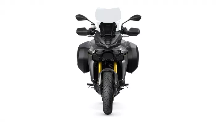 Front view of a grey adventure motorcycle with a tall windshield, dual side panniers, and gold front forks seen head-on.