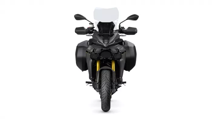 Front view of a black adventure motorcycle with a tall windscreen and dual headlights, flanked by side panniers.