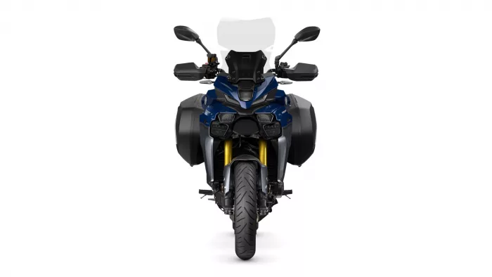 Front view of a blue adventure motorcycle with windshield, side panniers, and bold styling.
