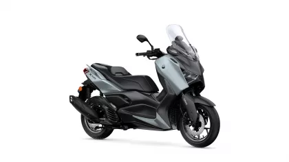 Side view of a gray Yamaha XMAX scooter with a tall clear windshield and black seat.