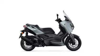 Side view of a silver and black Yamaha XMAX sport scooter with windshield and disc brakes exposed