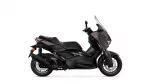 Side view of a dark burgundy Yamaha XMAX scooter with a tall windshield and disc brakes visible at the front wheel