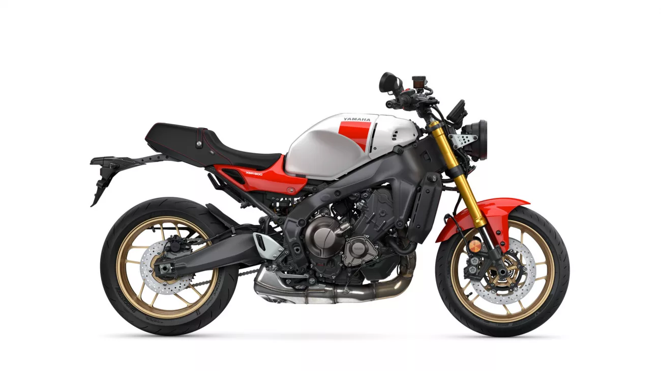 Side view of a Yamaha XSR900 motorcycle with white fuel tank, red accents, and gold front forks.