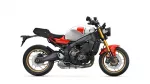 Side view of a Yamaha XSR900 motorcycle with white fuel tank, red accents, and gold front forks.