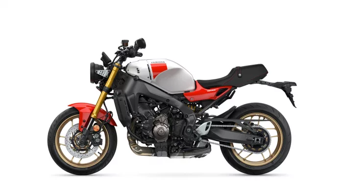 Side view of a Yamaha XSR900 sport motorcycle with a white fuel tank, red accents, gold front forks, and black frame.