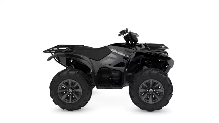 Black Yamaha Grizzly ATV with large off-road tires and front/rear racks from a side view