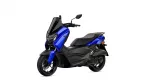 Blue Yamaha scooter photographed from a front-left angle, showing a tall windshield, blue body panels and black seat.