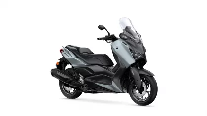 Grey Yamaha XMAX scooter shown from a three-quarter front angle with a tall clear windshield and black trim.
