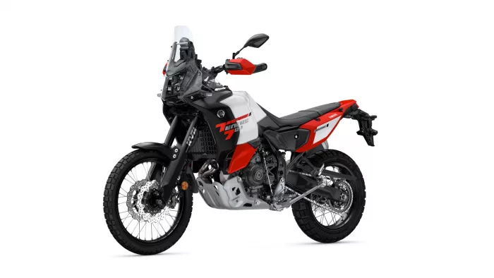 Adventure motorcycle shown from the front-right side with a tall windscreen and knobby tires in white, red, and black livery, resembling a Yamaha Tenere.
