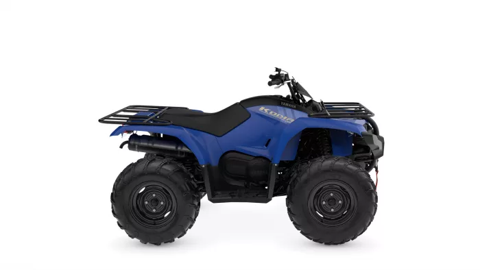 Blue Yamaha Kodiak ATV with large knobby tires and front/rear cargo racks.