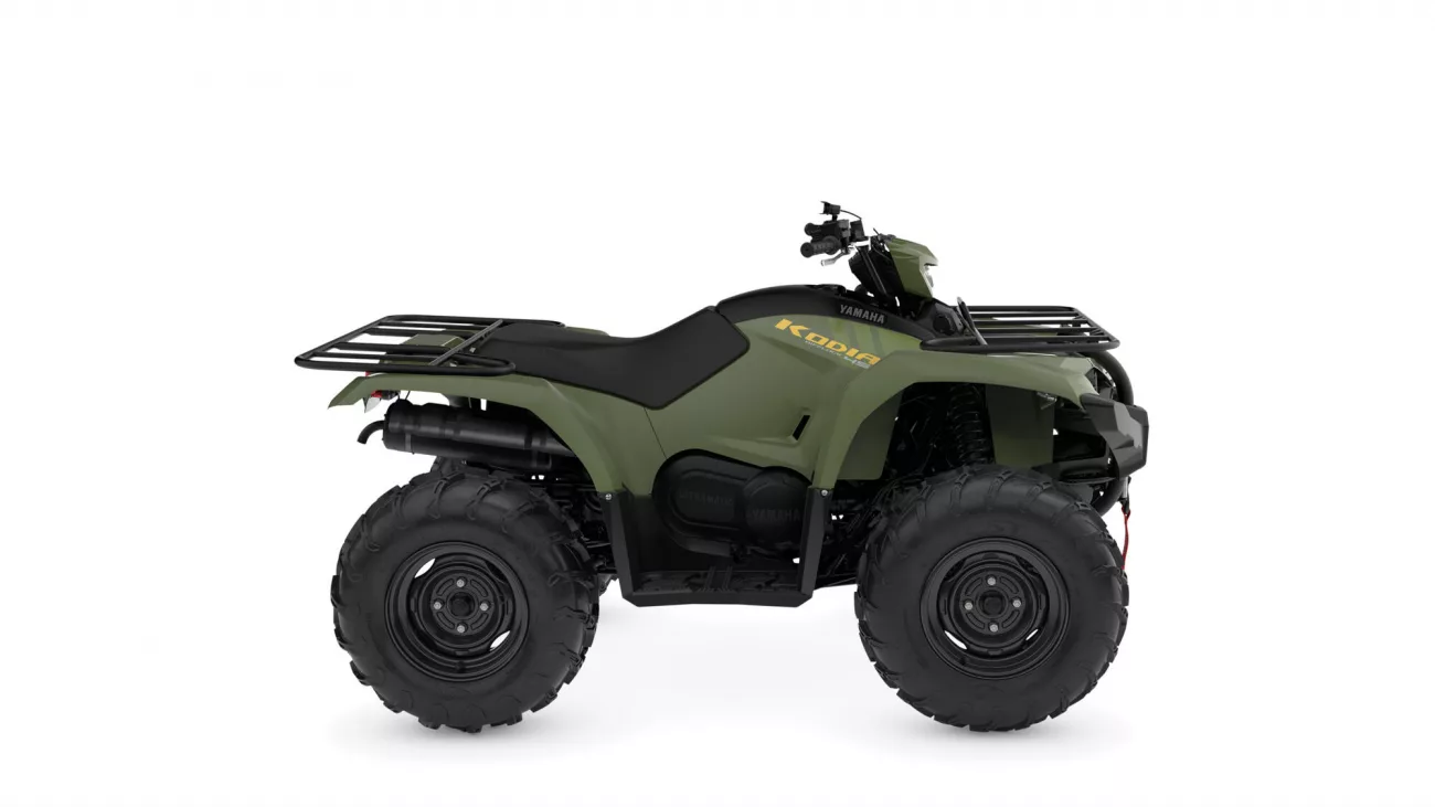 Olive-green Yamaha Kodiak ATV with black seat, cargo racks, and large rugged tires viewed from the side.