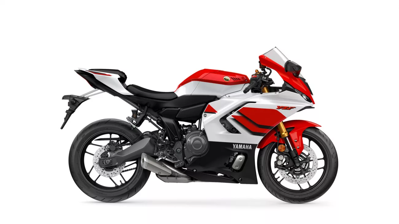 Side view of a red-and-white Yamaha sport motorcycle against a white background, showing the bike's sleek fairing and black seat.