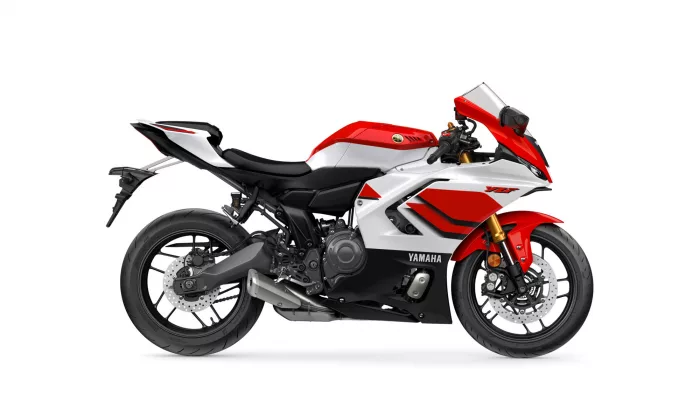 Side view of a red-and-white Yamaha sport motorcycle against a white background, showing the bike's sleek fairing and black seat.