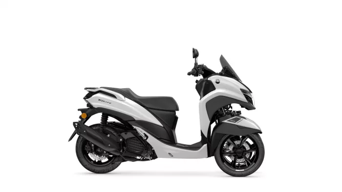 White and black Yamaha Tricity scooter shown from the side with a partial front view, highlighting the seat, rear suspension, and front fairing.