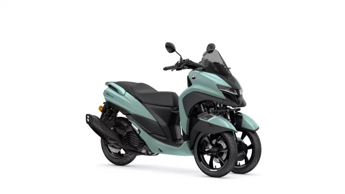 Front-three-quarter view of a teal Yamaha scooter with two front wheels and a tall windscreen, black seat and handlebars.