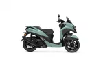 Side view of a mint-green Yamaha Tricity scooter, showing the teal body, black seat, front windshield, and wheel details
