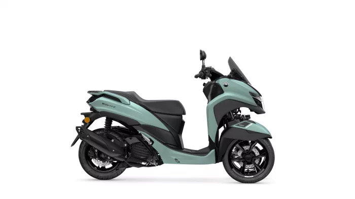Side view of a mint-green Yamaha Tricity scooter, showing the teal body, black seat, front windshield, and wheel details