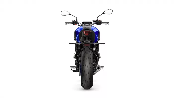 Rear view of a blue sport motorcycle, showing taillight, seat, and wide rear tire.