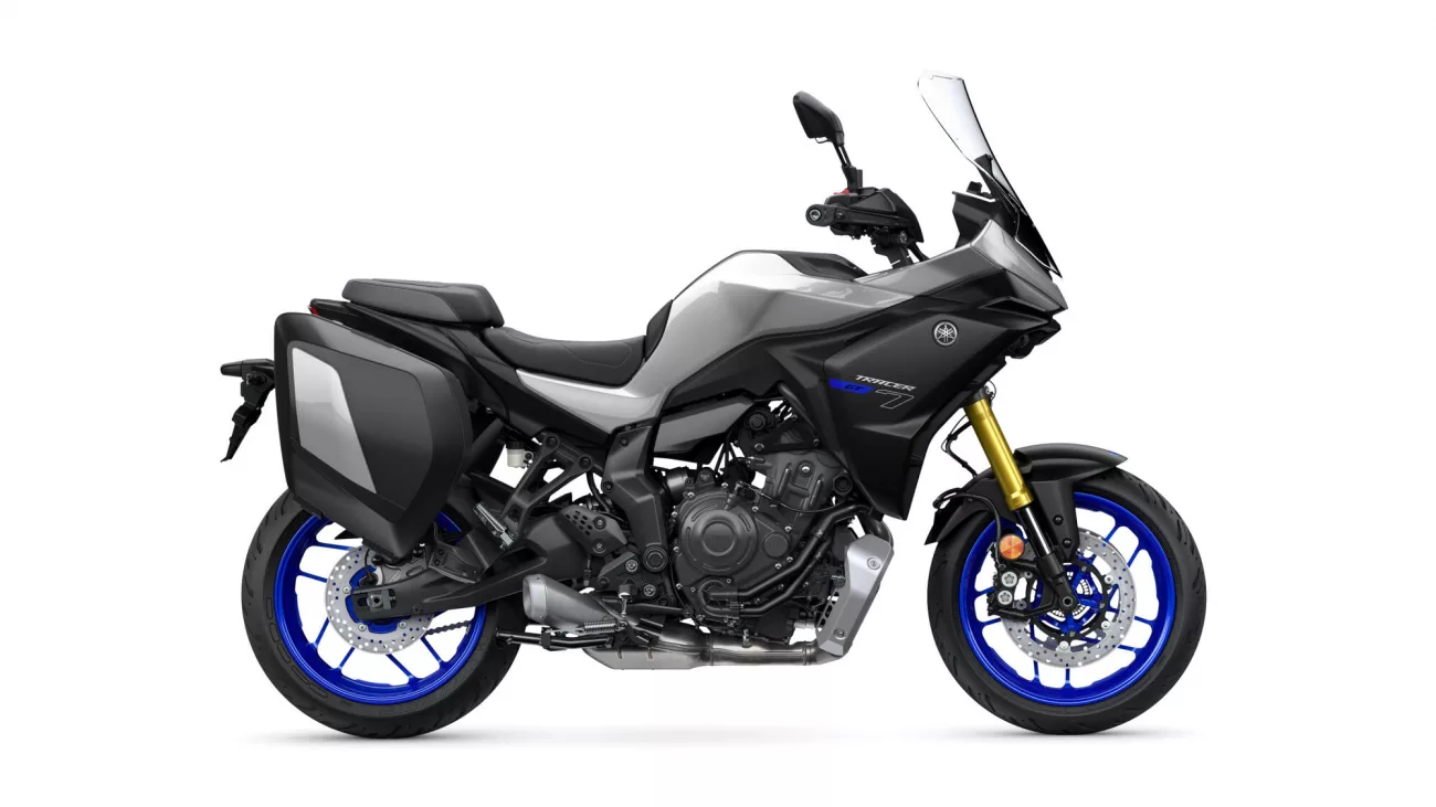 Side view of a Yamaha Tracer GT motorcycle with black/gray body, blue rims, and integrated side panniers, on white background