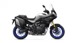 Side view of a Yamaha Tracer GT motorcycle with black/gray body, blue rims, and integrated side panniers, on white background