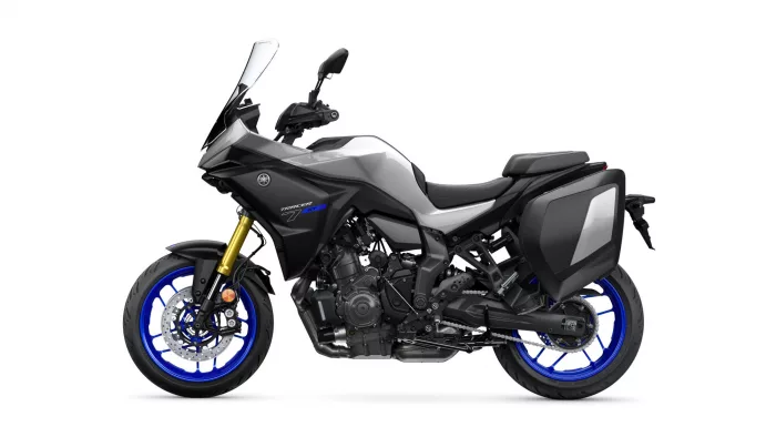 Sport motorcycle with gray bodywork, black frame, blue rims, front windshield, and rear side cases for storage.