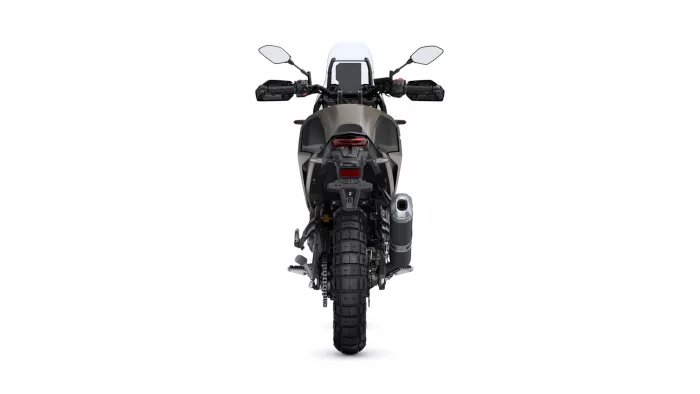 Rear view of an adventure motorcycle with a large knobby rear tire, panniers, and a red taillight cluster