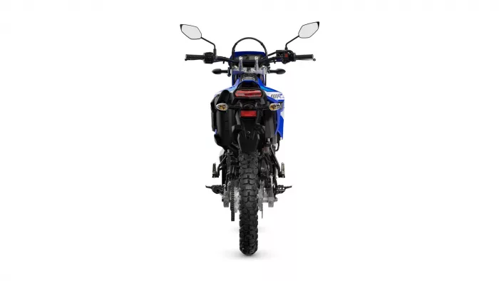 Rear view of a blue dirt bike with knobby tires, tail light, and side mirrors visible from behind,