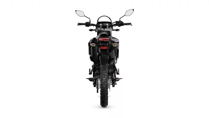 Rear view of a black adventure motorcycle with a red tail light on a white background, showing knobby rear tire and mirrors above.