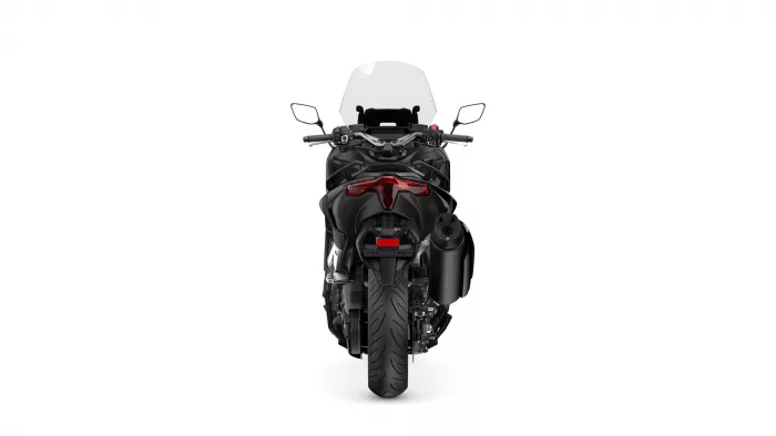 Rear view of a black sport motorcycle with a tall windshield, red taillight, and wide rear tire against a white background.
