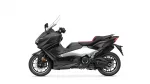Side view of a black Yamaha Tmax sport scooter with a tall windshield and red-accented seat on a white background