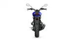 Rear view of a blue motorcycle showing the taillight, exhaust, and wide rear tire against a white background study.