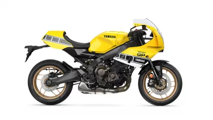 Side view of a bright yellow Yamaha XSR900 GP motorcycle, showing its black frame, gold wheels, and GP decals on the fairing.